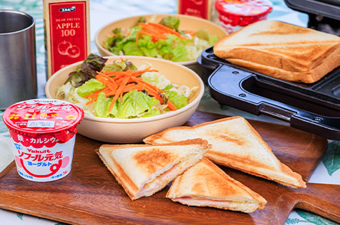 Breakfast table with hot sandwiches, salad, and yogurt.