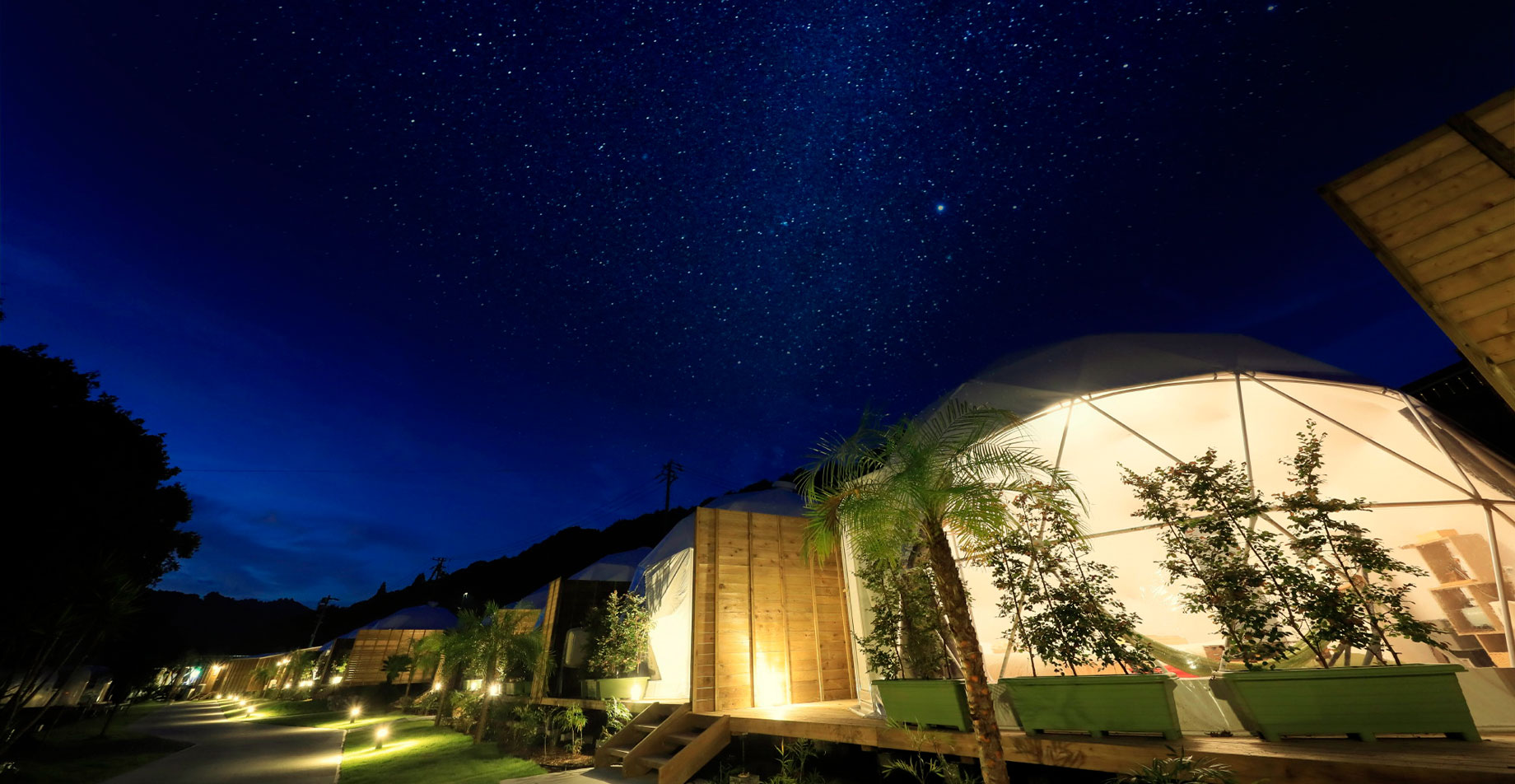 Illuminated dome tent at night under a starry sky.