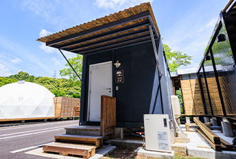 Exterior of a modern black container house against a blue sky.