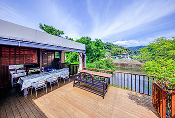 Spacious wooden deck facing a river with a long BBQ table setup.