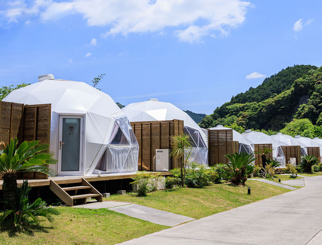 Multiple white glamping dome tents lined up on the resort grounds.