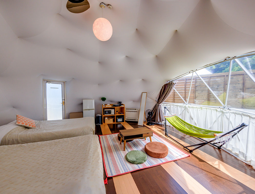 Inside of a dome tent with twin beds on the left and a green hammock set up by the window on the right.
