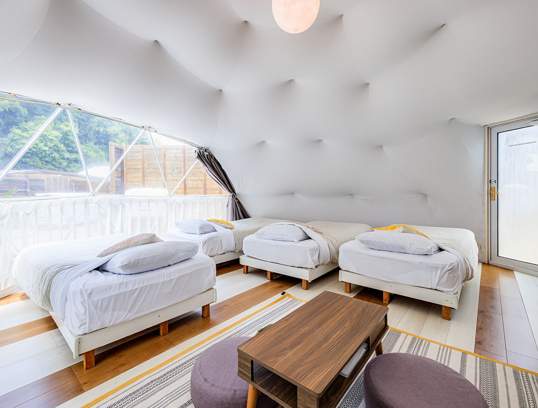 The interior of a dome tent featuring a low table and several beds.